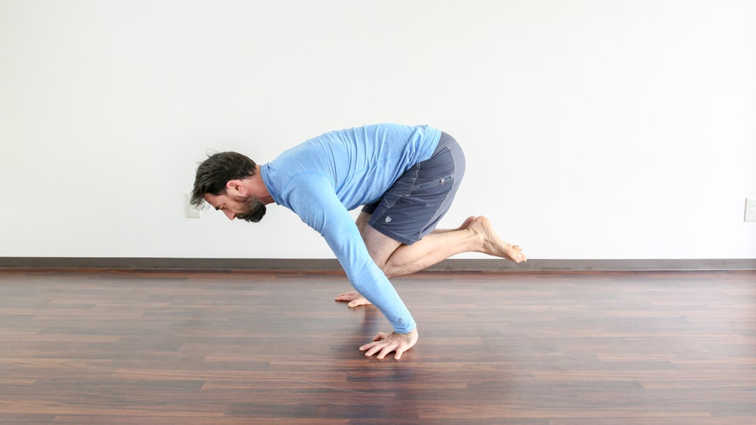 a man in a blue shirt is doing a yoga pose