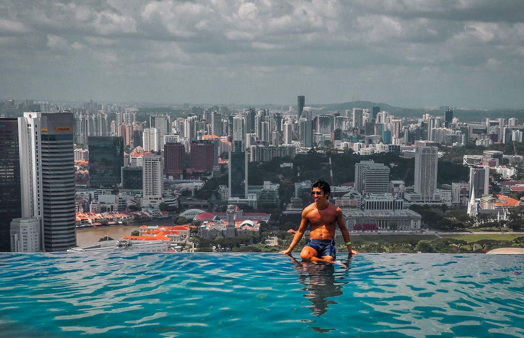 woman in black bikini top sitting on swimming pool during daytime